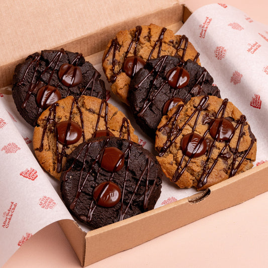 Box of assorted cookies with chocolate drizzle on a branded paper