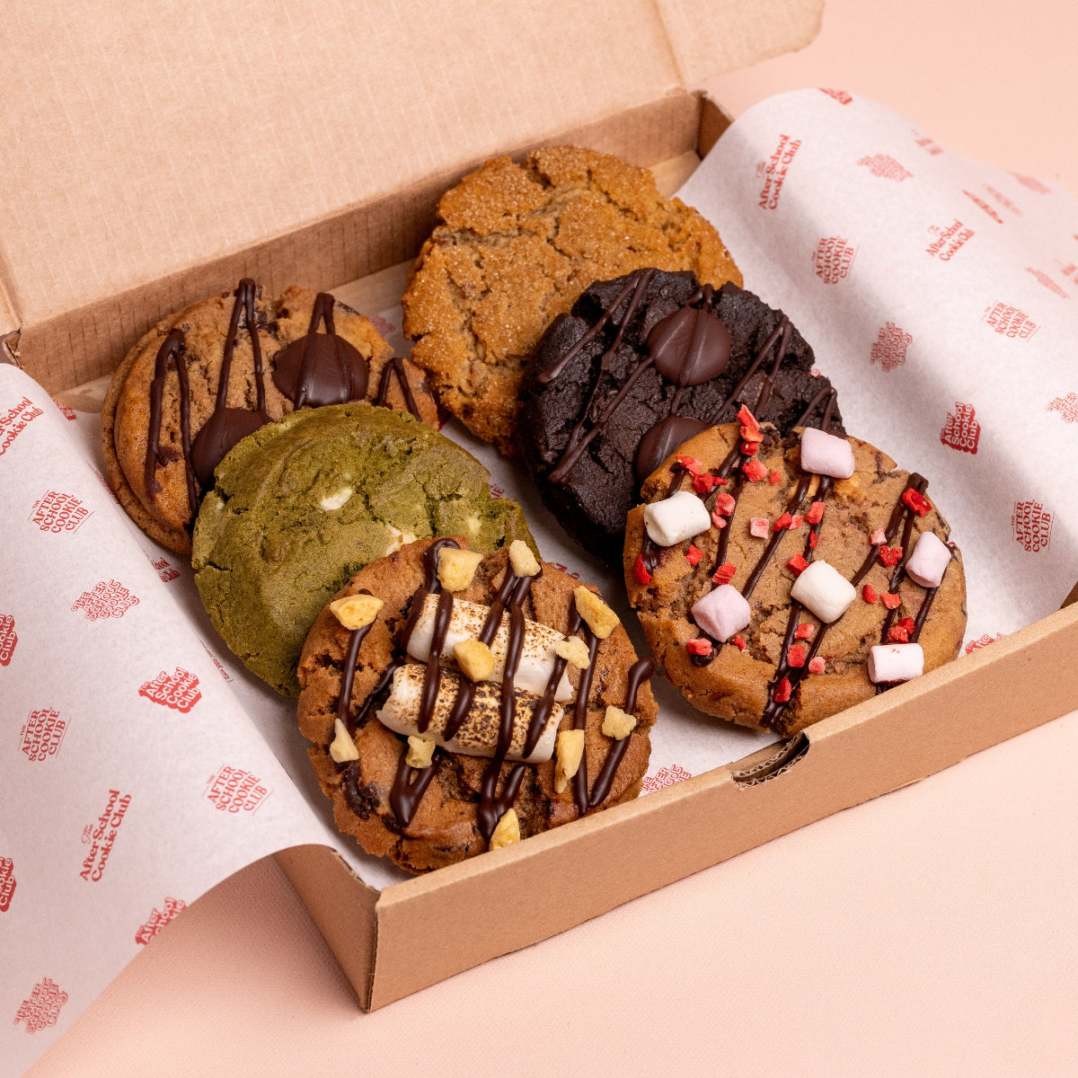 Box of assorted cookies with different toppings on a pink background