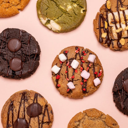 Assorted cookies with different toppings on a pink background