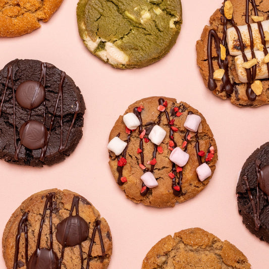 Assorted cookies with different toppings on a pink background