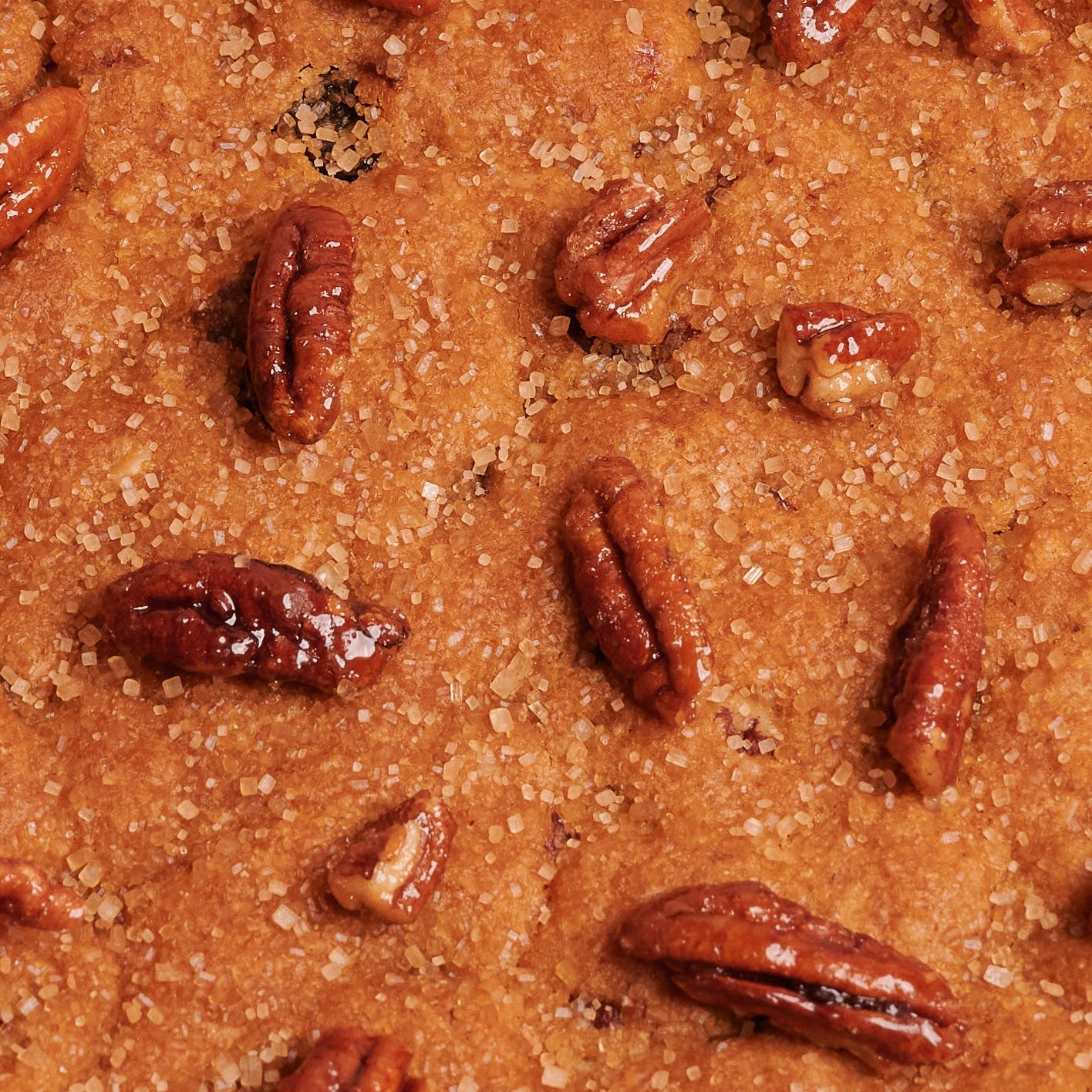 Detail of Giant cookie with pecan nuts and demerara sugar in a box on pink background