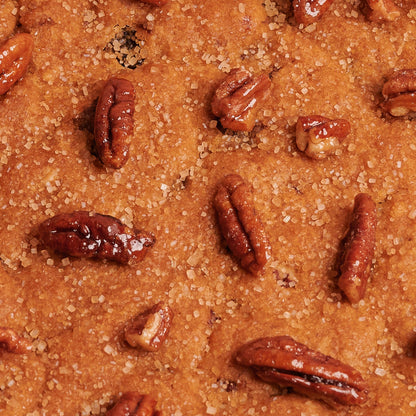 Detail of Giant cookie with pecan nuts and demerara sugar in a box on pink background