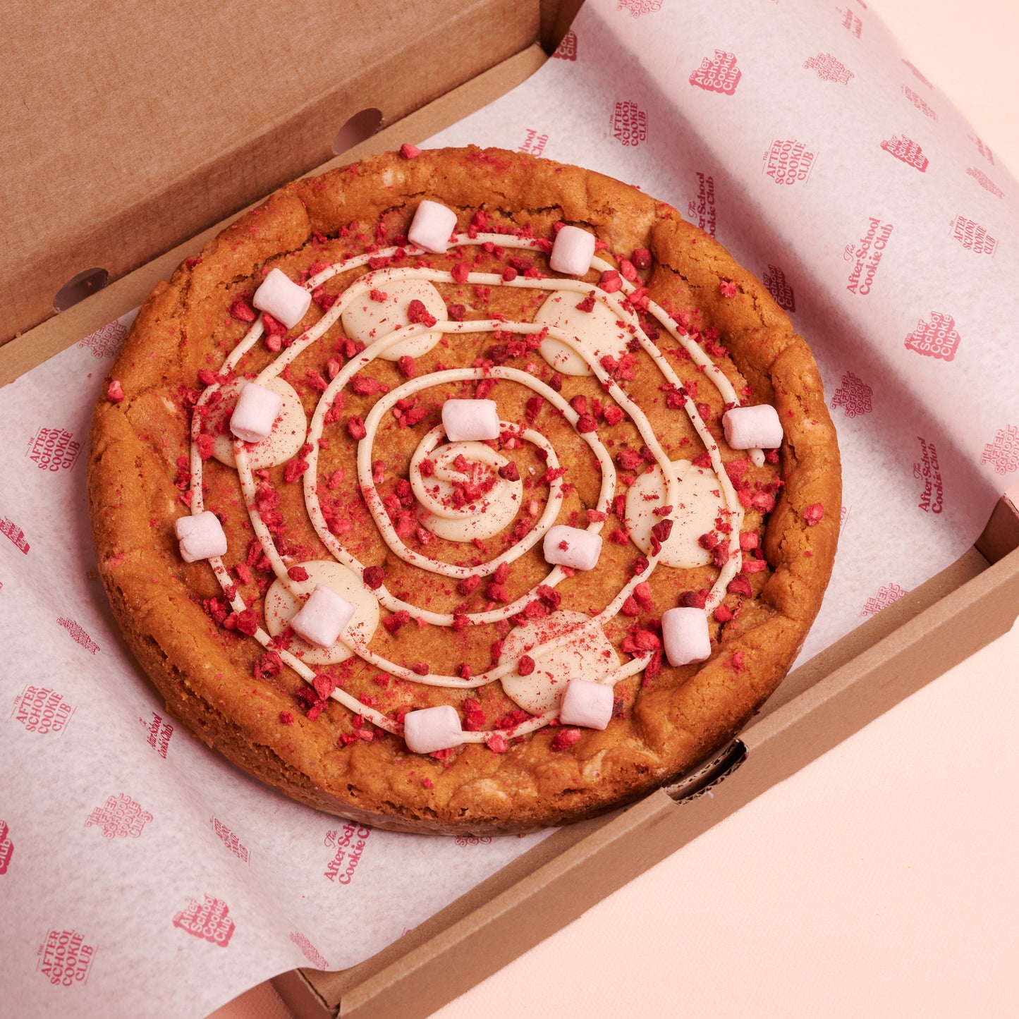 Giant white choc cookie in a box on pink background