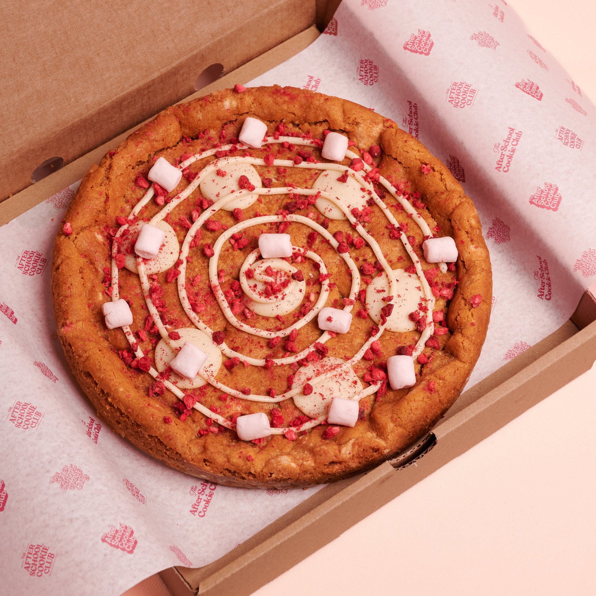 Giant white choc cookie in a box on pink background